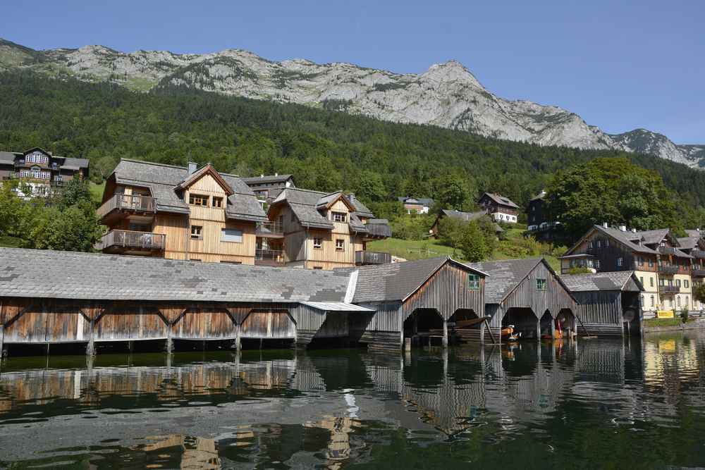 Vorne stehen die rustikalen Bootshäuser am Grundlsee, dahinter die Wohnhäuser, zu sehen auf der Drei Seen Tour