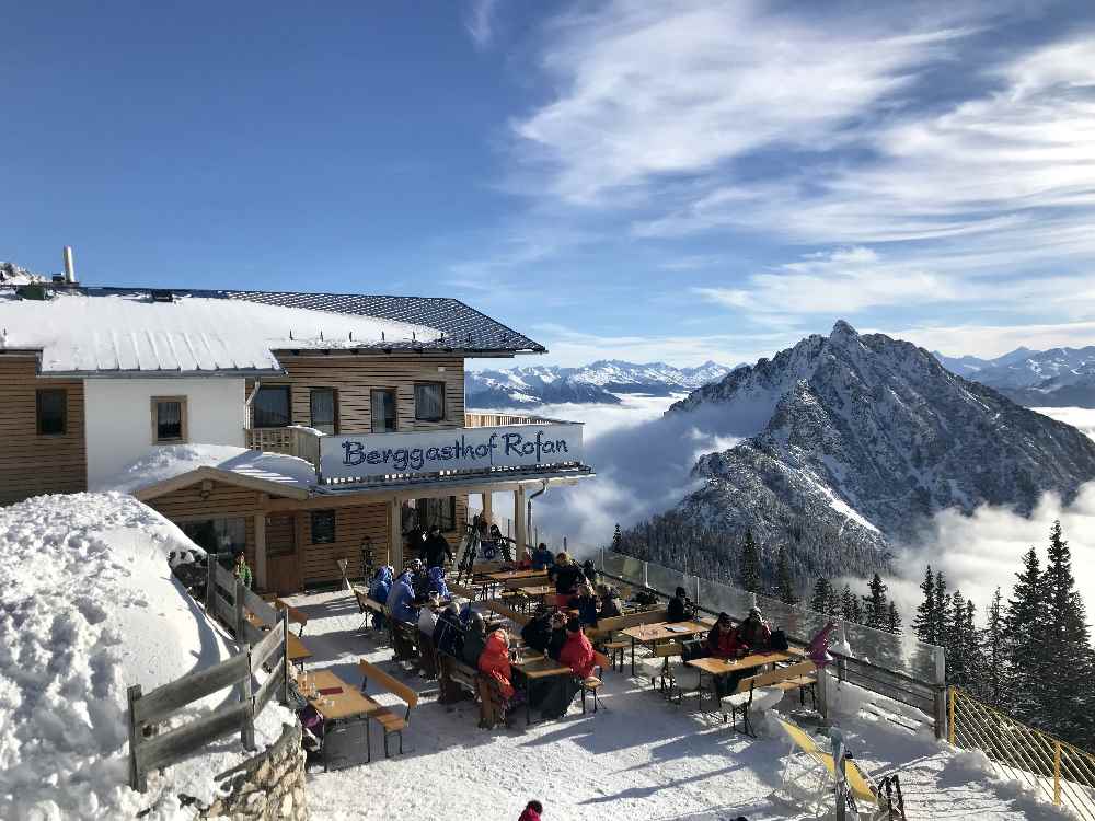 Das ist die Sonnenterrase beim Berggasthof Rofan mit dem verschneiten Rofangipfel