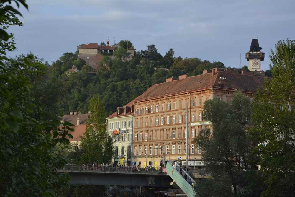 Unser Start in den Familienurlaub Graz - wir stehen an der Mur und schauen hinauf zum Schlossberg