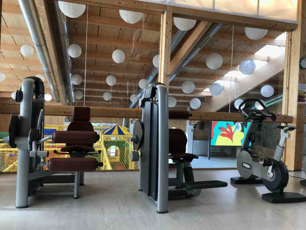 Nebenan ist die große Halle mit Fitnesstudio, Kletterwand und Indoor-Spielplatz: Von den Fitnessgeräten kannst du hinunter schauen