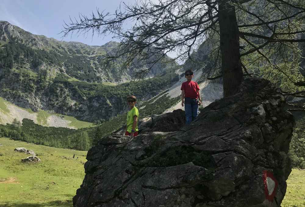 Bei der Holzeralm liegt ein hausgroßer Stein - den die Kinder zu einer Klettereinlage nutzen 