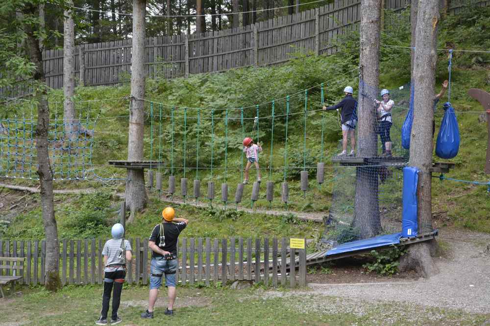 Teenager und kleinere Kinder können zusammen im Kletterpark üben. Es gibt verschiedene Schwierigkeitsgrade.
