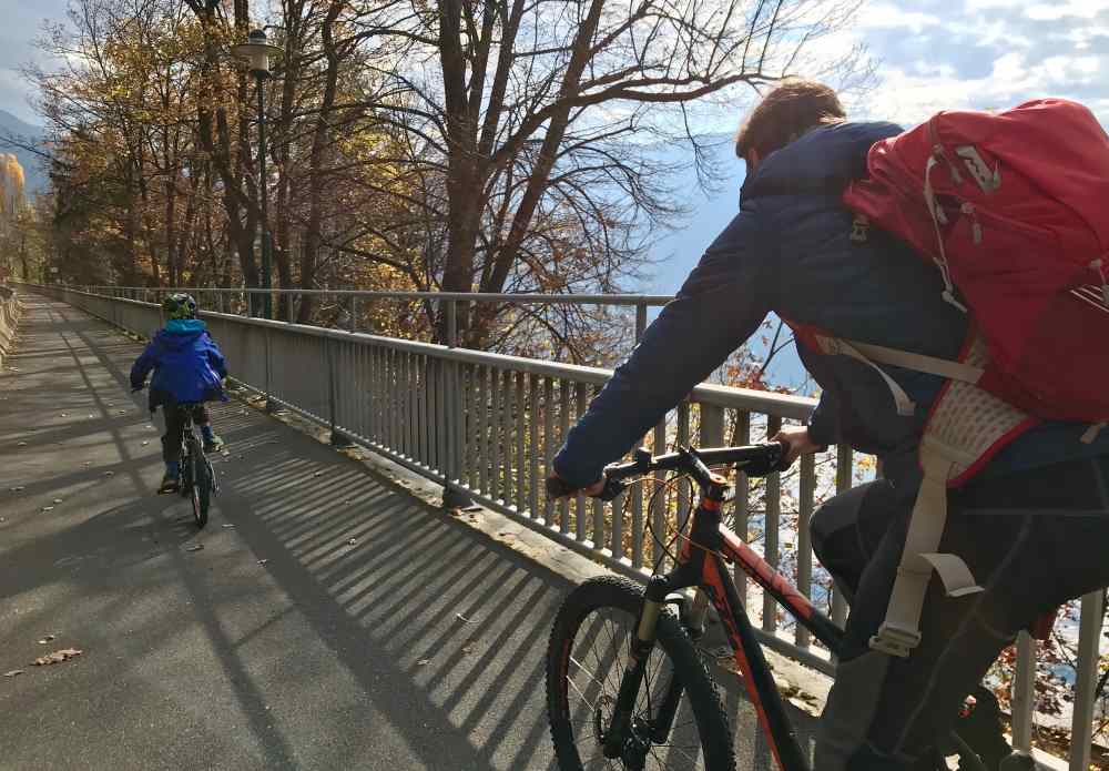 Wir fahren am späten Vormittag mit dem Fahrrad am Ufer des Millstätter See der Sonne entgegen