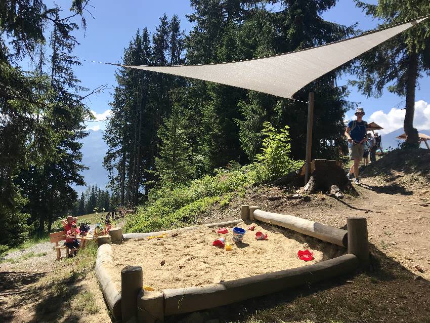 Durchdachtes Abenteuer am Berg mit Kindern - sogar ein Sandspielplatz mit Sonnensegel neben der Pausenbank