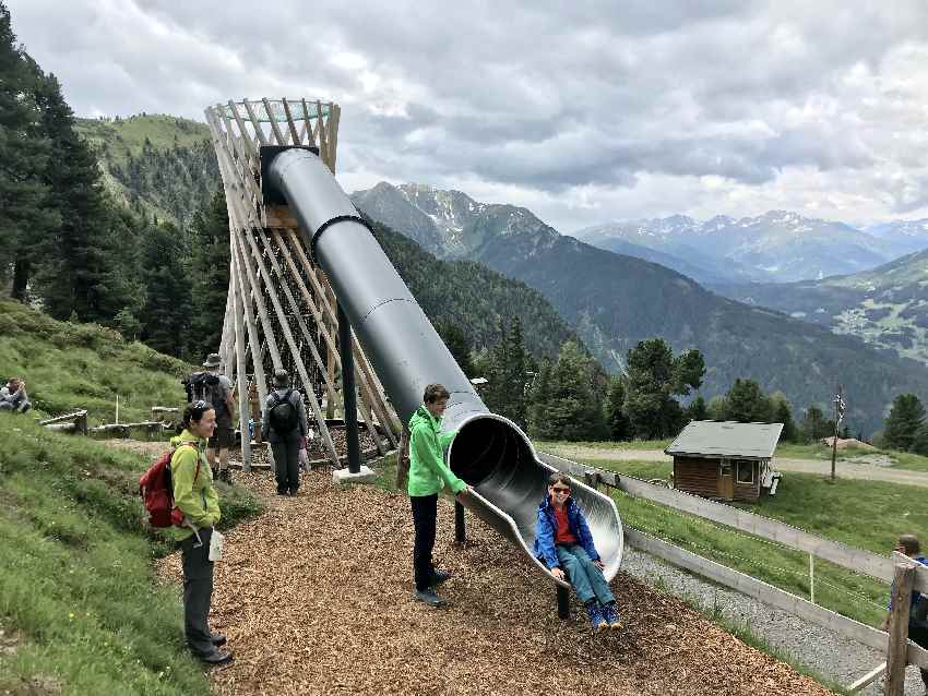 Ein großer Spielturm mit langer Rutsche und Ausblick auf die Berge