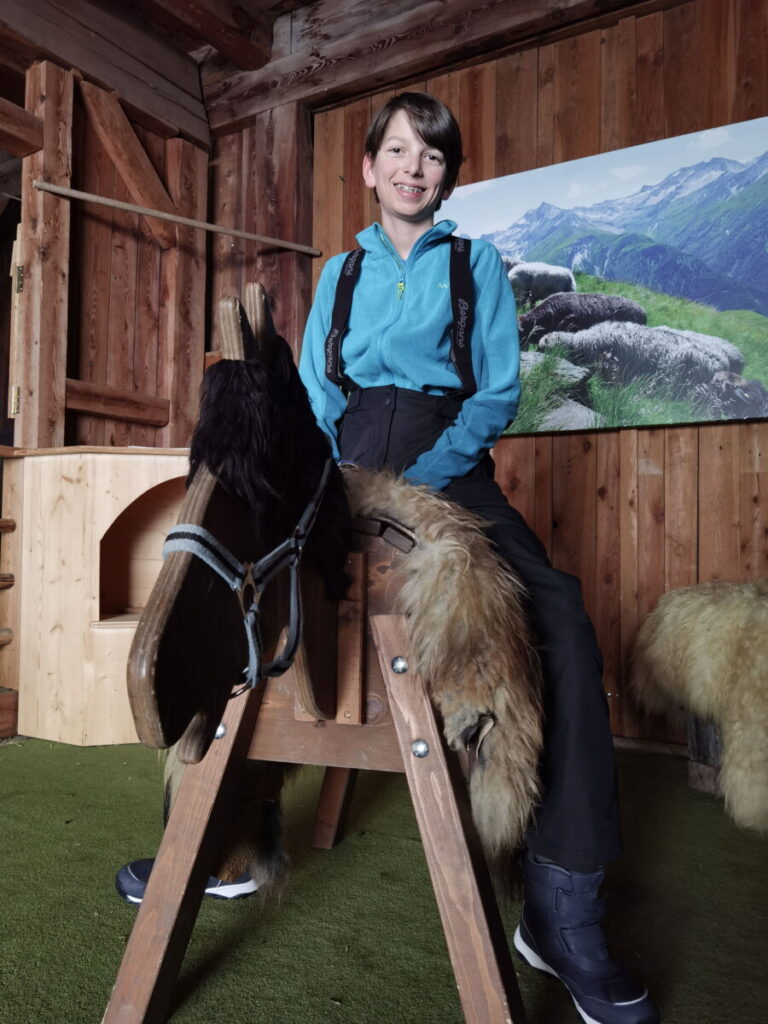 Auf dem Kinderbauernhof spielen und auf dem Holzpferd reiten