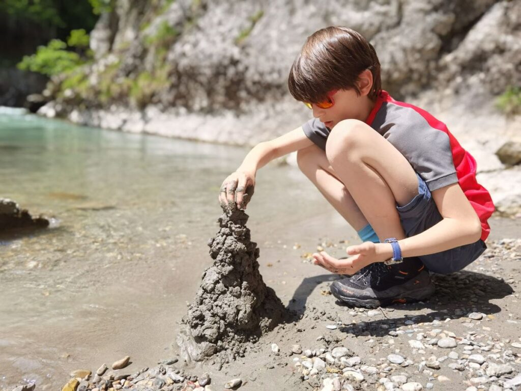 Matschtürme bauen am Ufer der Kössen Klamm