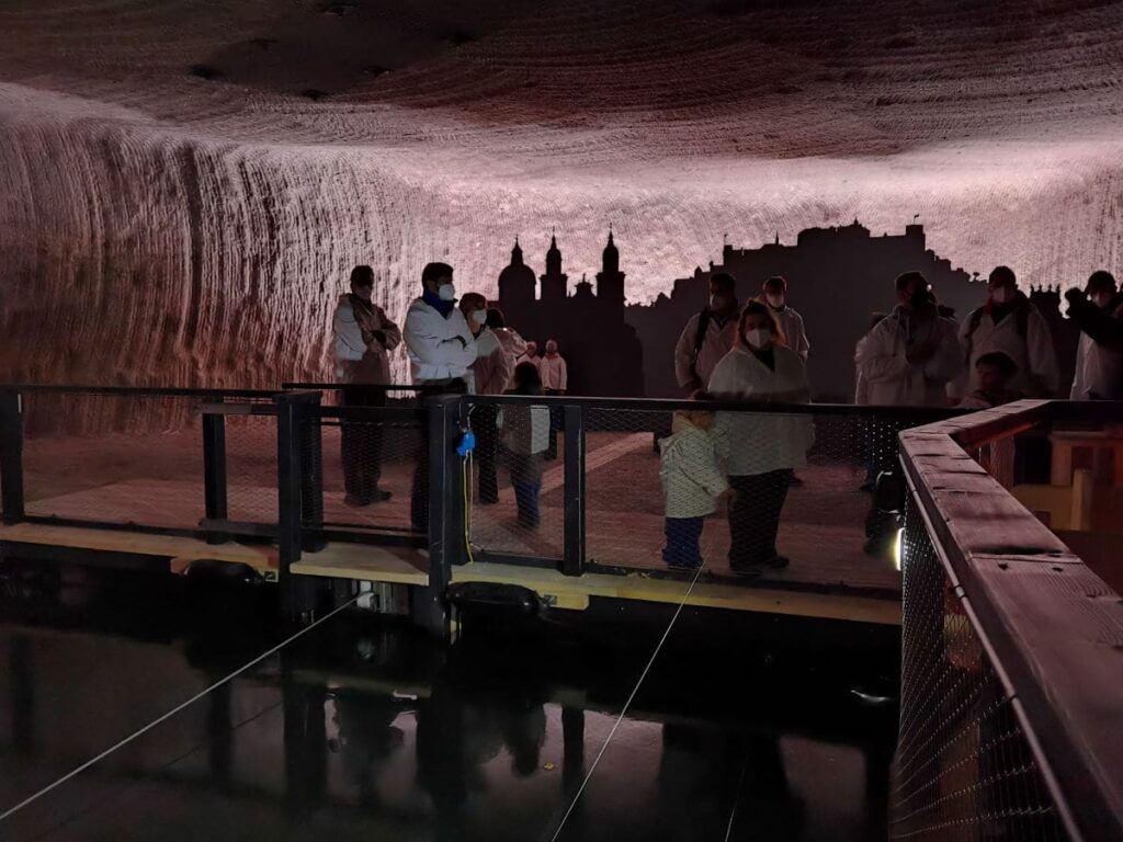 Highlight im Salzbergwerk Salzburg: Mit dem Boot über den Salzsee mit der Sihouette der Stadt am Horizont