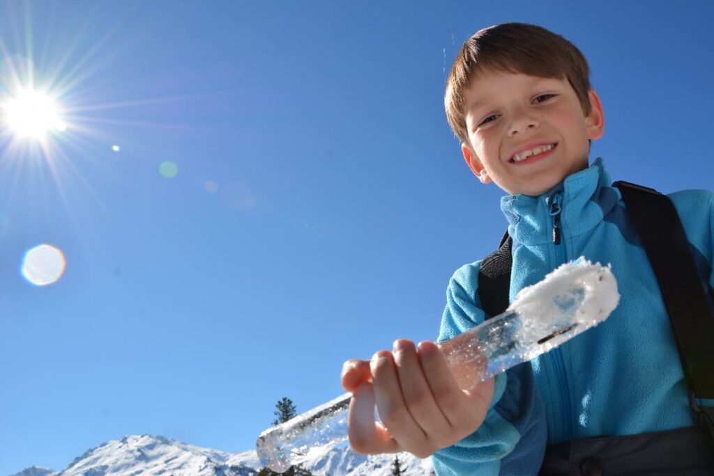 Rodeln mit Kindern - dazu gehört auch das Spielen im Schnee, samt der Suche nach großen Eiszapfen...